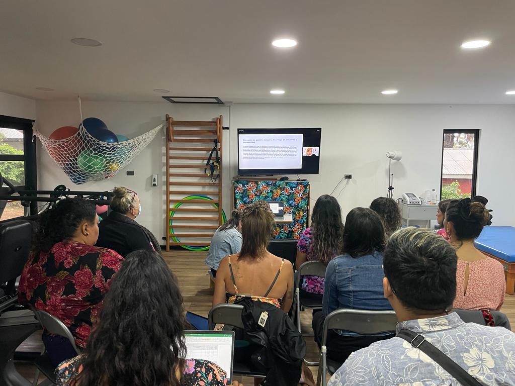 Personas miradas desde la espalda, sentadas frente a un proyector viendo la exposición de Carlos Kaiser Director Ejecutivo ONG Inclusiva